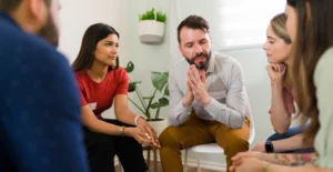 Group therapy session with individuals seated in a circle, actively listening and sharing—illustrating peer support and open communication in the rehab center’s recovery programs.